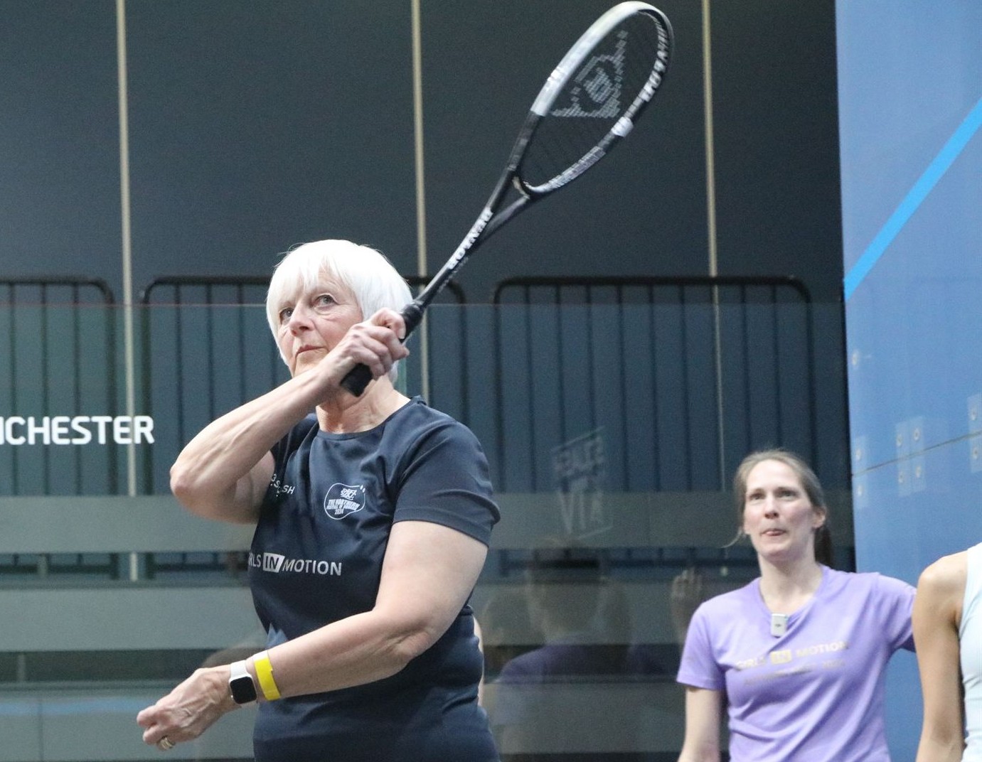 A female racketball coach giving a coaching session to women players on a UK squash court